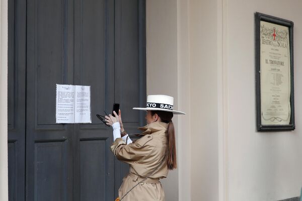 Девушка фотографирует объявление об отмене спектаклей в театре Ла Скала в Милане Девушка фотографирует объявление об отмене спектаклей в театре Ла Скала в Милане