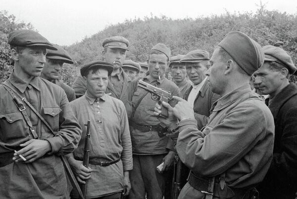 Командир партизанского отряда знакомит бойцов с оружием. Смоленская область, Россия Командир партизанского отряда знакомит бойцов с оружием. Смоленская область, Россия