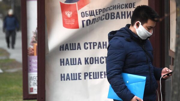 Молодой человек в защитной маске стоит у агитационного плаката Молодой человек в защитной маске стоит у агитационного плаката