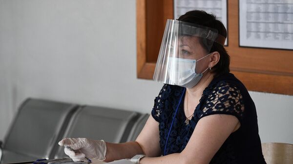 Женщина в защитной маске во время демонстрации работы модельного участка для общероссийского голосования по поправкам в Конституцию РФ в лицее No9 Новосибирска