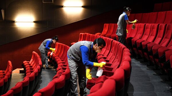 Сотрудники клининговой службы производит санитарную обработку кресел в кинотеатре