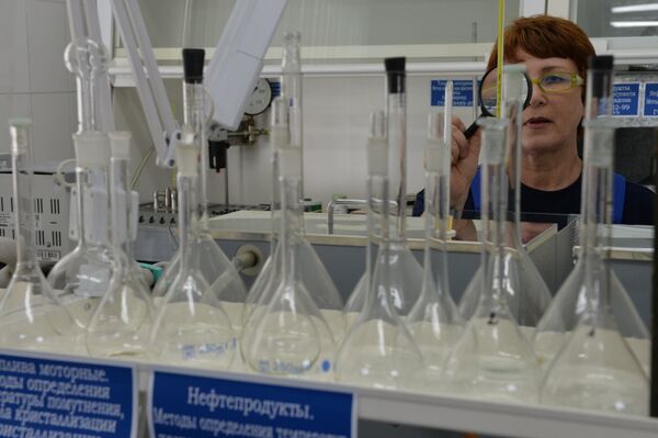 Сотрудница испытательной лаборатории нефтепродуктов во время работы с пробой топлива Сотрудница испытательной лаборатории нефтепродуктов во время работы с пробой топлива