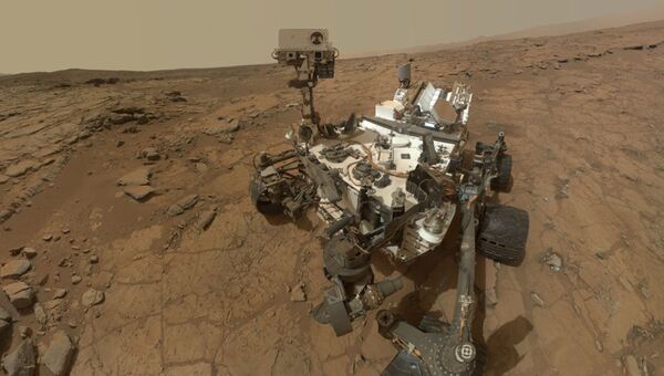 Марсоход Curiosity во время изучения камня Джон Кляйн на поверхности красной планеты Марсоход Curiosity во время изучения камня Джон Кляйн на поверхности красной планеты