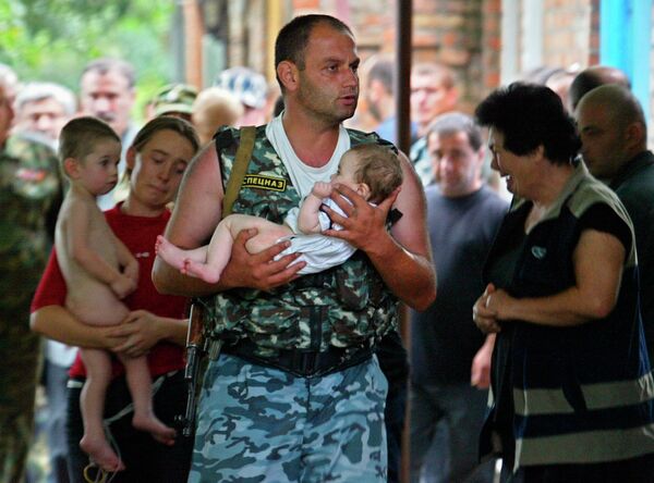 Боец спецназа несет спасенного ребенка во время штурма захваченной боевиками школы в Беслане. 2004 год Боец спецназа несет спасенного ребенка во время штурма захваченной боевиками школы в Беслане. 2004 год