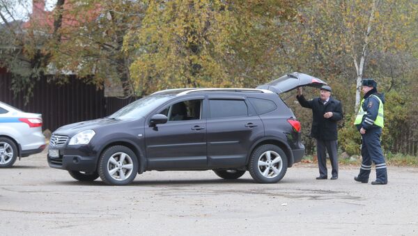 Сотрудник ДПС досматривает машину автовладельца на одной из улиц деревни Тимошкино Сотрудник ДПС досматривает машину автовладельца на одной из улиц деревни Тимошкино