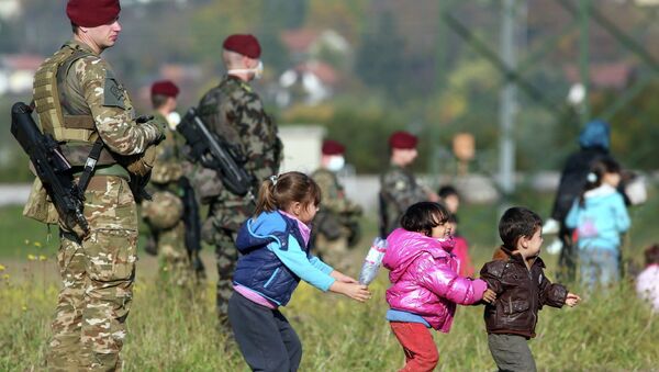 Дети беженцев играют рядом со словенскими военными на хорватско-словенской границе Дети беженцев играют рядом со словенскими военными на хорватско-словенской границе