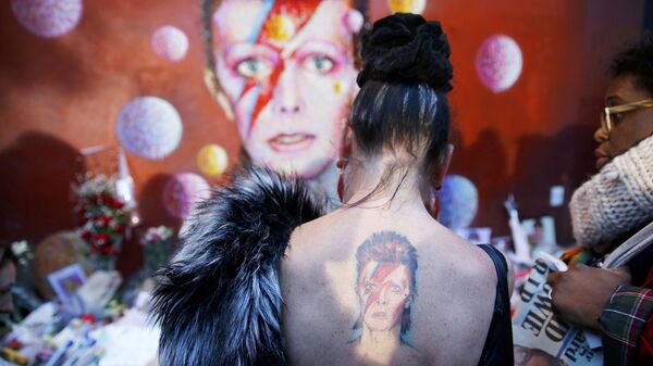 Женщина с татуировкой Ziggy Stardust у стены Дэвида Боуи в Брикстоне. Лондон, январь 2016 Женщина с татуировкой Ziggy Stardust у стены Дэвида Боуи в Брикстоне. Лондон, январь 2016
