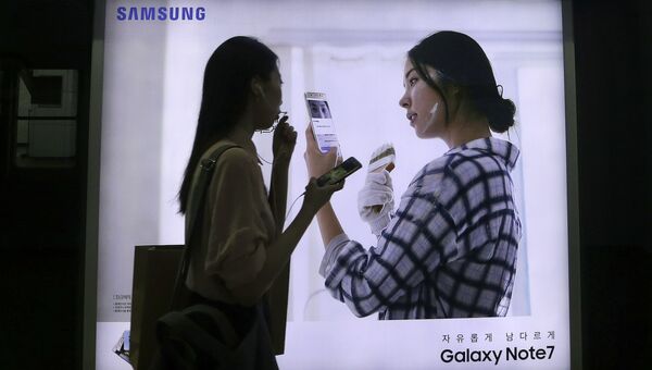 Девушка на фоне рекламы смартфона Galaxy Note 7 компании Samsung. Архивное фото Девушка на фоне рекламы смартфона Galaxy Note 7 компании Samsung. Архивное фото