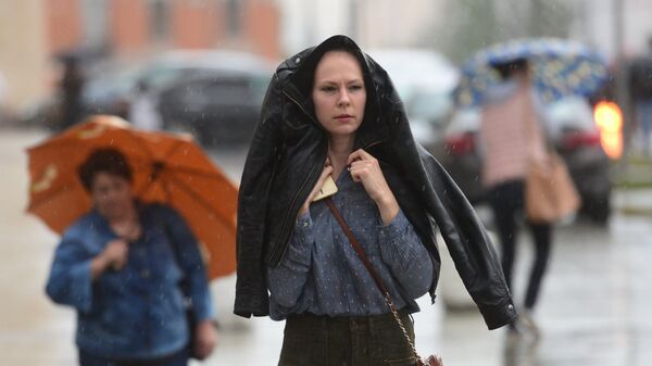 Прохожие идут на Смоленской площади во время дождя в Москве