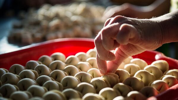 Женщина складывает пельмени на поднос Женщина складывает пельмени на поднос