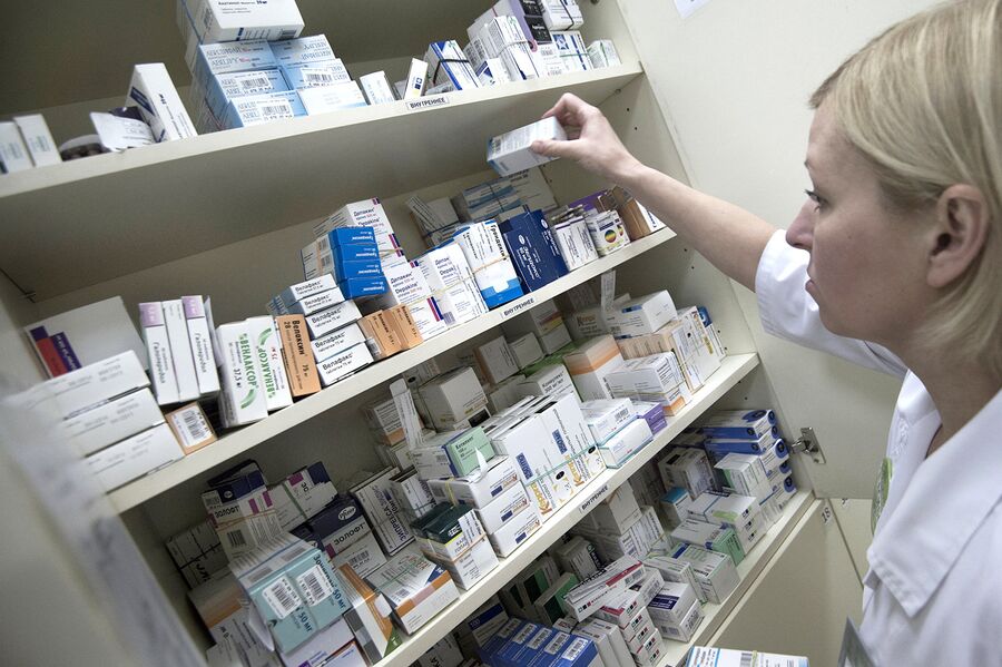 Сотрудница аптеки разбирает лекарства Сотрудница аптеки разбирает лекарства