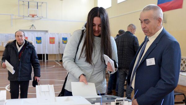 Девушка опускает бюллетень в урну на выборах президента РФ на избирательном участке во Владивостоке. Девушка опускает бюллетень в урну на выборах президента РФ на избирательном участке во Владивостоке.
