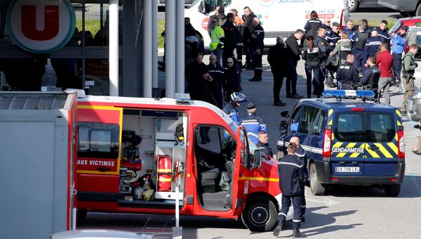 Сотрудники полиции у супермаркета в коммуне Треб на юге Франции, где произошел захват заложников. 23 марта 2018 Сотрудники полиции у супермаркета в коммуне Треб на юге Франции, где произошел захват заложников. 23 марта 2018