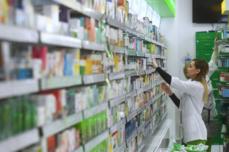 Фармацевт раскладывает лекарственные препараты в аптеке сети Ригла на Арбате в Москве Фармацевт раскладывает лекарственные препараты в аптеке сети Ригла на Арбате в Москве