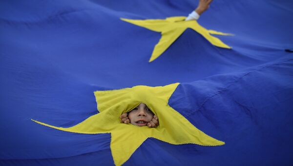 Дети выглядывают из прорезей во флаге ЕС во время акции протеста в Бухаресте, Румыния Дети выглядывают из прорезей во флаге ЕС во время акции протеста в Бухаресте, Румыния