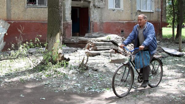 Мужчина едет на велосипеде во дворе жилого дома, пострадавшего в результате обстрела, в поселке Горловка Донецкой области. Архивное фото Мужчина едет на велосипеде во дворе жилого дома, пострадавшего в результате обстрела, в поселке Горловка Донецкой области. Архивное фото