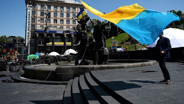 Молодой человек с украинским флагом у памятника основателям Киева на площади Независимости Молодой человек с украинским флагом у памятника основателям Киева на площади Независимости