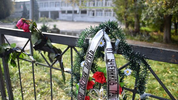Траурный венок и цветы на ограде недалеко от Керченского политехнического колледжа