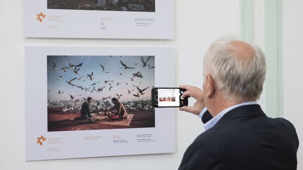 Посетитель у фотографии Себнем Коскун Завтрак на крыше на выставке работ победителей конкурса имени Андрея Стенина в Буэнос-Айресе Посетитель у фотографии Себнем Коскун Завтрак на крыше на выставке работ победителей конкурса имени Андрея Стенина в Буэнос-Айресе