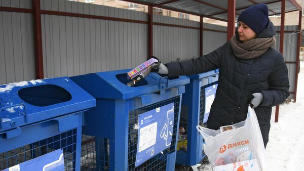Женщина выбрасывает мусор в баки для раздельного сбора отходов