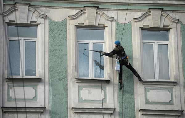 Промышленный альпинист моет окна здания на улице Воздвиженка в Москве Промышленный альпинист моет окна здания на улице Воздвиженка в Москве