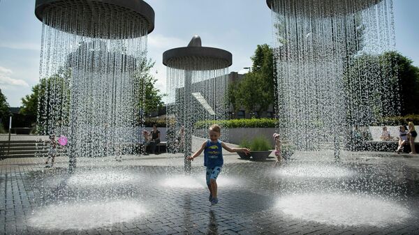 Ребенок играет в фонтане в Вильнюсе, Литва