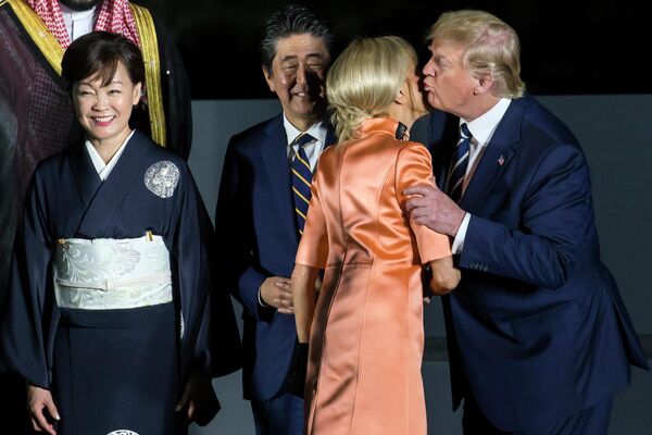 Президент США Дональд Трамп целует супругу Эммануила Макрона Бриджит на саммите G-20 в Осаке Президент США Дональд Трамп целует супругу Эммануила Макрона Бриджит на саммите G-20 в Осаке