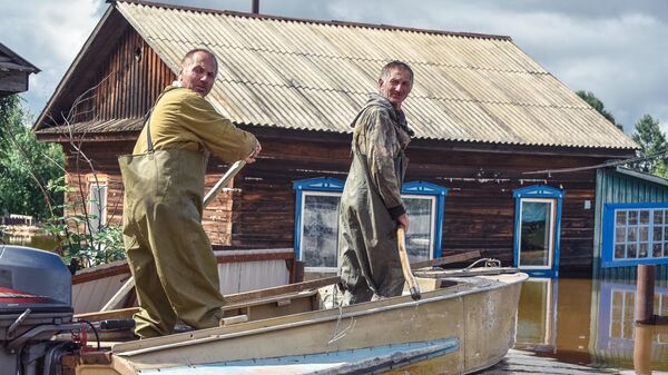 Местные жители плывут на лодке по  затопленной улице в селе Норск в Селемджинском районе Амурской области