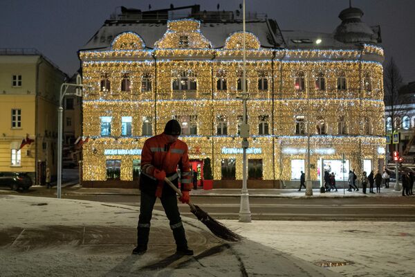 Сотрудник коммунальной службы подметает тротуар на улице Пречистенка в Москве Сотрудник коммунальной службы подметает тротуар на улице Пречистенка в Москве