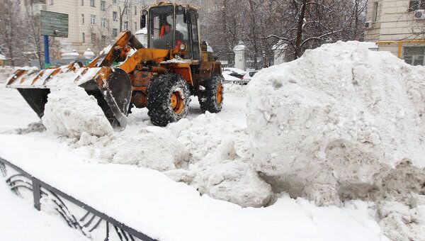 Трактор убирает снег во дворе одного из домов Трактор убирает снег во дворе одного из домов