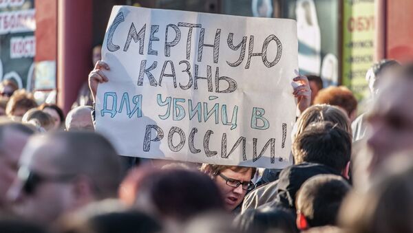 Мужчина держит плакат с требованием смертной казни для виновных в убийствах. Архивное фото Мужчина держит плакат с требованием смертной казни для виновных в убийствах. Архивное фото